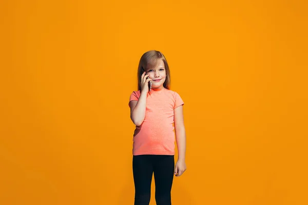 Den glada teen flicka står och ler mot orange bakgrund. — Stockfoto