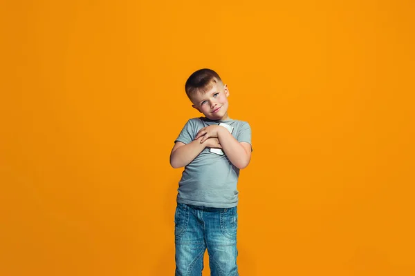 O menino adolescente feliz de pé e sorrindo contra o fundo laranja . — Fotografia de Stock