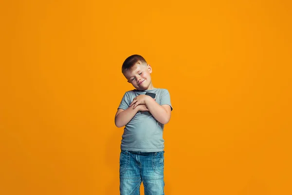 De gelukkige tiener jongen permanent en glimlachend tegen oranje achtergrond. — Stockfoto