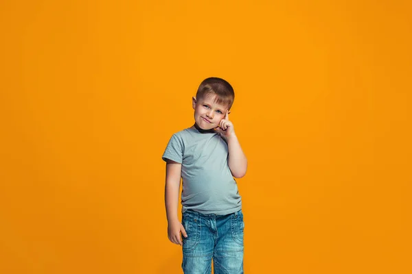 O menino adolescente feliz de pé e sorrindo contra o fundo laranja . — Fotografia de Stock