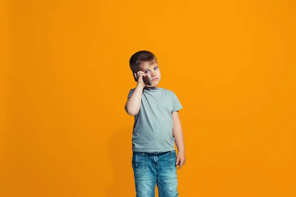 De gelukkige tiener jongen permanent en glimlachend tegen oranje achtergrond. — Stockfoto