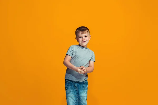 De gelukkige tiener jongen permanent en glimlachend tegen oranje achtergrond. — Stockfoto