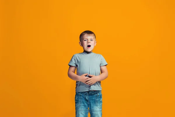 O menino adolescente feliz de pé e sorrindo contra o fundo laranja . — Fotografia de Stock