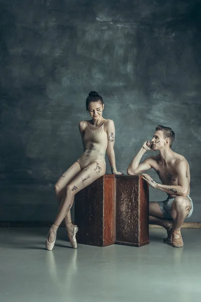Молодые современные артисты балета позируют на фоне серой студии — стоковое фото