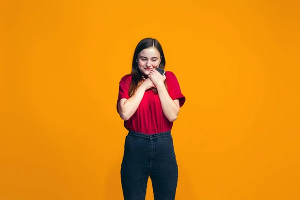 The happy teen girl standing and smiling against orange background. — Stock Photo, Image