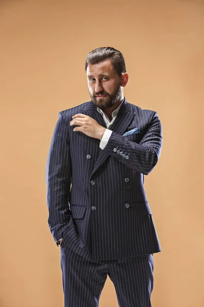 Conceito de beleza masculina. Retrato de um jovem elegante com corte de cabelo elegante vestindo terno na moda posando sobre fundo pastel . — Fotografia de Stock