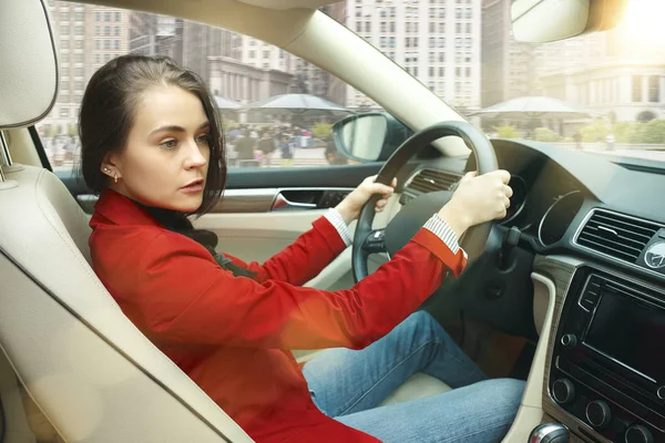 Driving around city. Young attractive woman driving a car