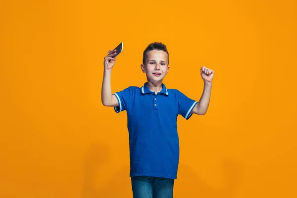 Den glada teen pojke står och ler mot orange bakgrund. — Stockfoto