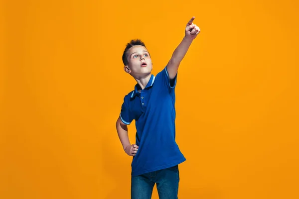 Den glada teen pojke pekar du, halv längd närbild porträtt på orange bakgrund. — Stockfoto