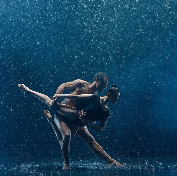 Casal jovem de bailarinos dançando unde rwater gotas — Fotografia de Stock