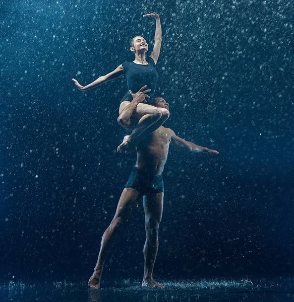 Casal jovem de bailarinos dançando unde rwater gotas — Fotografia de Stock