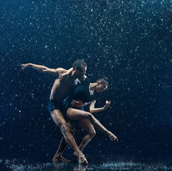 Casal jovem de bailarinos dançando unde rwater gotas — Fotografia de Stock