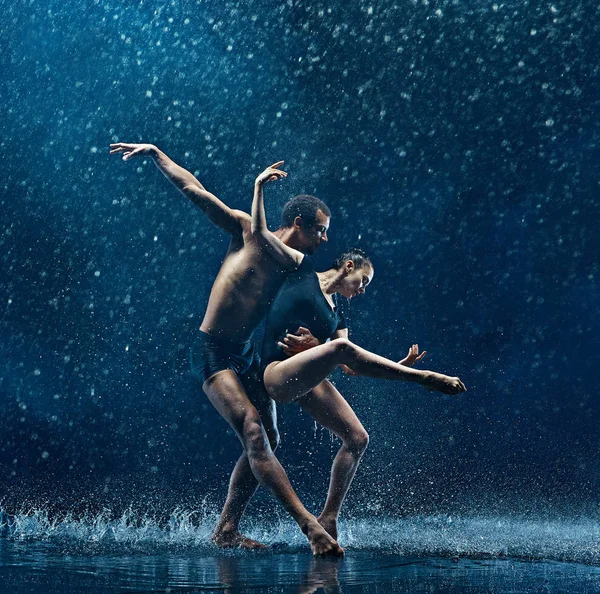 Casal jovem de bailarinos dançando unde rwater gotas — Fotografia de Stock