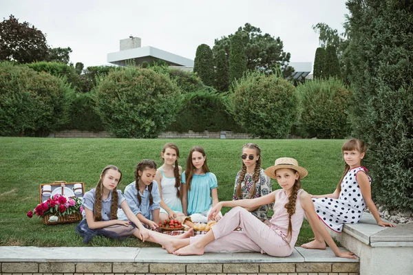 子供ファッションのコンセプトです 公園で緑の芝生に座ってティーンの女の子のグループ 子供のカラフルな服 ライフ スタイル 流行色の概念 — ストック写真
