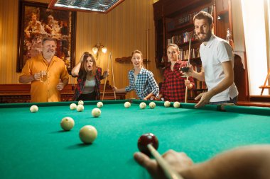 Genç erkek ve kadınların işten sonra ofiste bilardo oynarken.