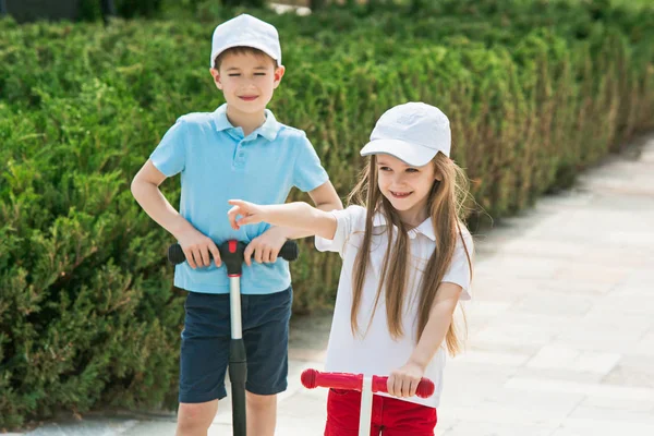 Préscolaire fille et garçon équitation scooter à l'extérieur . — Photo