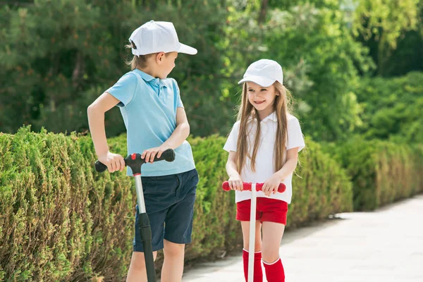 Niña preescolar y niño montando scooter al aire libre . —  Fotos de Stock