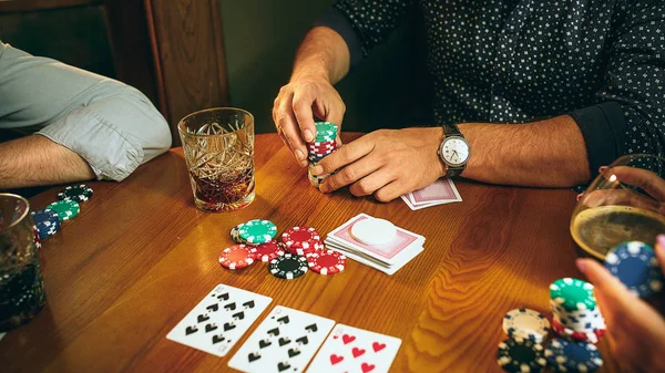 Foto vista lateral de amigos sentados à mesa de madeira. Amigos se divertindo enquanto joga jogo de tabuleiro . — Fotografia de Stock