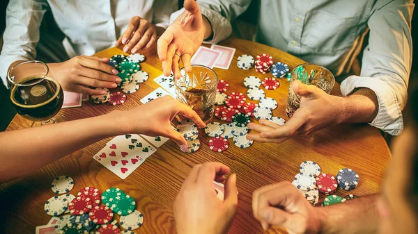 Side view photo of friends sitting at wooden table. Friends having fun while playing board game.