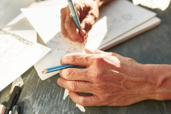 Primer plano del hombre que trabaja de Arquitecto bosquejando un proyecto de construcción en su proyecto de avión en obras de construcción de obra — Foto de Stock