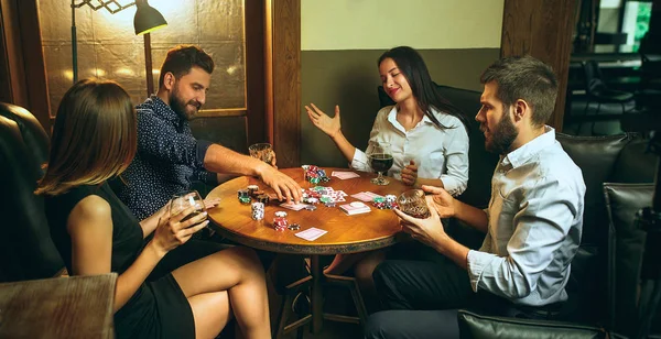 Foto vista lateral de amigos sentados à mesa de madeira. Amigos se divertindo enquanto joga jogo de tabuleiro . — Fotografia de Stock