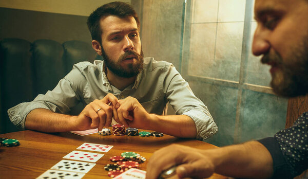 Side view photo of friends sitting at wooden table. Friends having fun while playing board game.