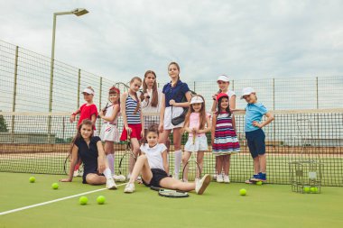 Kız tenis oyuncular tenis raketi açık kortu yeşil çim karşı holding olarak grup portresi