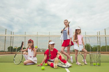 Kız tenis oyuncular tenis raketi açık kortu yeşil çim karşı holding olarak grup portresi
