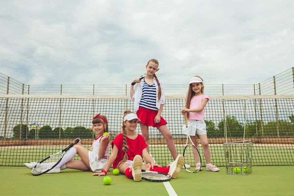 Retrato de grupo de chicas como tenistas sosteniendo raqueta de tenis contra hierba verde de la cancha al aire libre — Foto de Stock