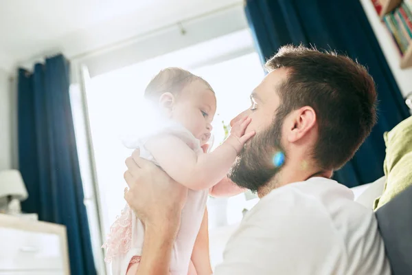 Proud father holding his newborn baby daughter up in the air at home — Stock Photo, Image