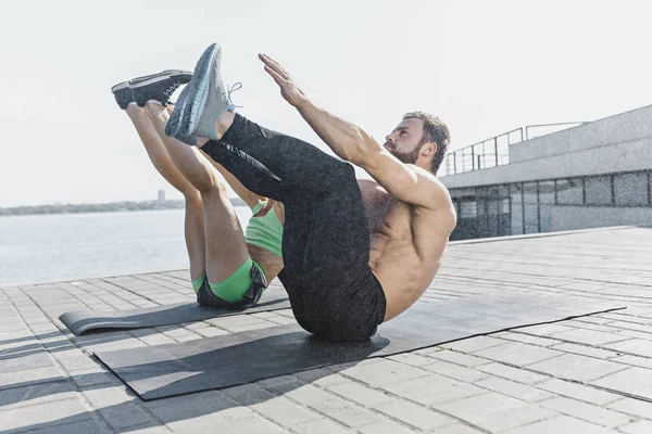 Fit fitness mujer y hombre haciendo ejercicios de estiramiento al aire libre en la ciudad — Foto de Stock