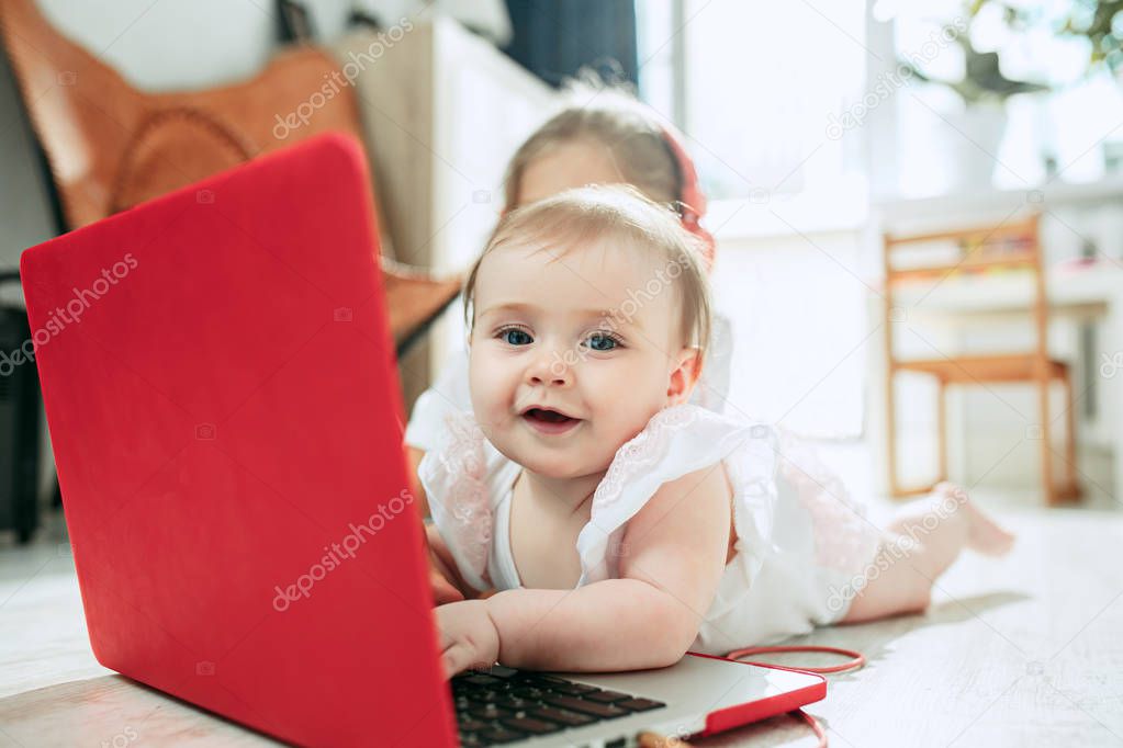 Portrait of little baby girl looking at camera with a laptop