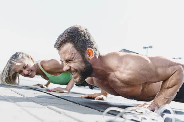 Fit fitness mujer y hombre haciendo ejercicios de fitness al aire libre en la ciudad — Foto de Stock