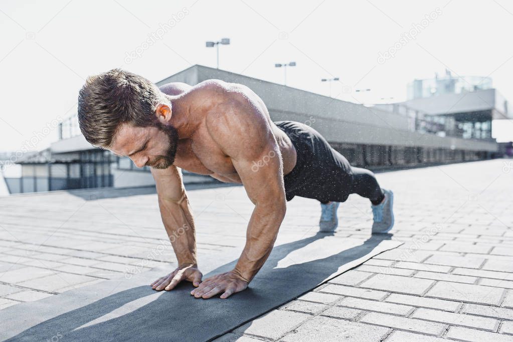 Fit fitness man doing fitness exercises outdoors at city