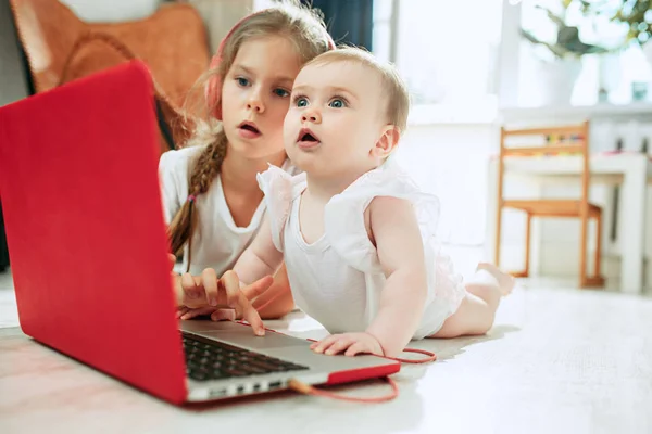 Portrait of little baby girl looking at camera with a laptop — Stock Photo, Image