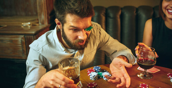 Side view photo of friends sitting at wooden table. Friends having fun while playing board game.