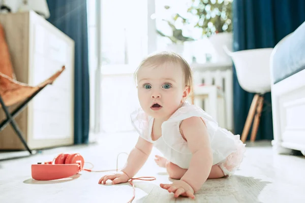 Søt, ung baby som sitter på gulvet hjemme og leker med hodetelefoner – stockfoto