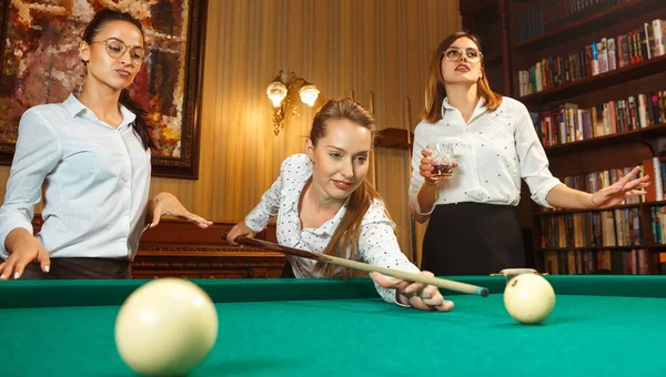 Young women playing billiards at office after work.