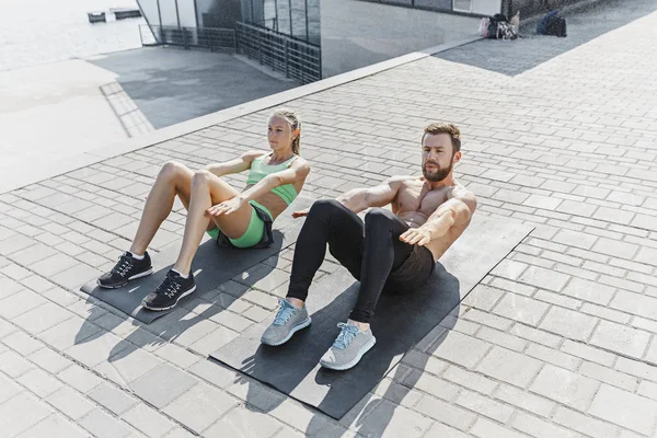 Fit fitness mujer y hombre haciendo ejercicios de fitness al aire libre en la ciudad — Foto de Stock