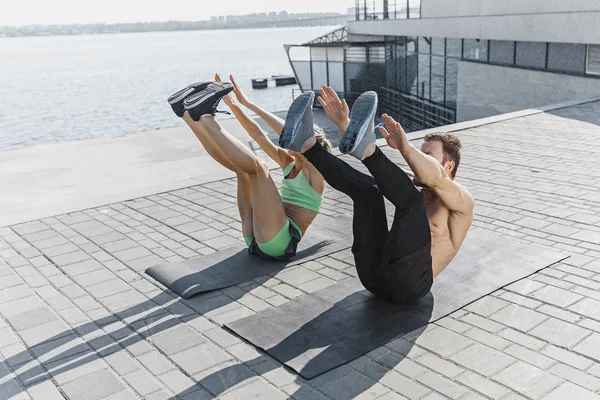Fit fitness mujer y hombre haciendo ejercicios de fitness al aire libre en la ciudad — Foto de Stock