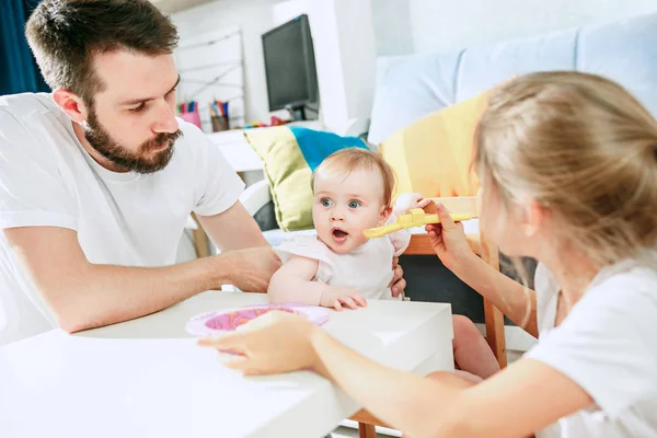 Bello giovane uomo che fa colazione e alimenta la sua bambina a casa — Foto Stock