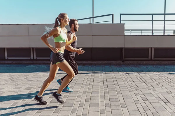 Pretty sporty woman and man jogging at city — Stock Photo, Image