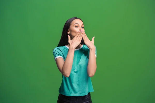 Молода жінка шепоче таємницю за її рукою на зеленому тлі — стокове фото