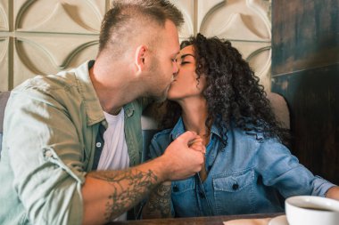 Mutlu genç çift kahve içme ve kafede otururken gülümseyen