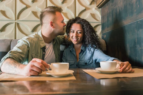 Glückliches junges Paar trinkt Kaffee und lächelt im Café — Stockfoto
