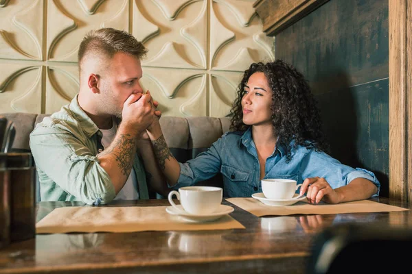 Feliz joven pareja está bebiendo café y sonriendo mientras se sienta en el café —  Fotos de Stock