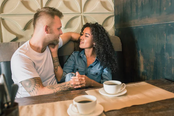 Feliz joven pareja está bebiendo café y sonriendo mientras se sienta en el café —  Fotos de Stock