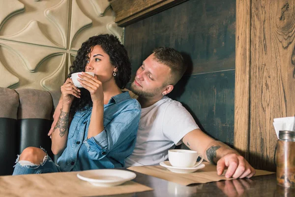 Feliz joven pareja está bebiendo café y sonriendo mientras se sienta en el café —  Fotos de Stock