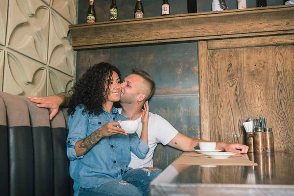 Feliz jovem casal está bebendo café e sorrindo enquanto sentado no café — Fotografia de Stock