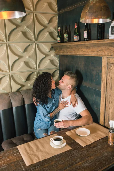 Feliz jovem casal está bebendo café e sorrindo enquanto sentado no café — Fotografia de Stock